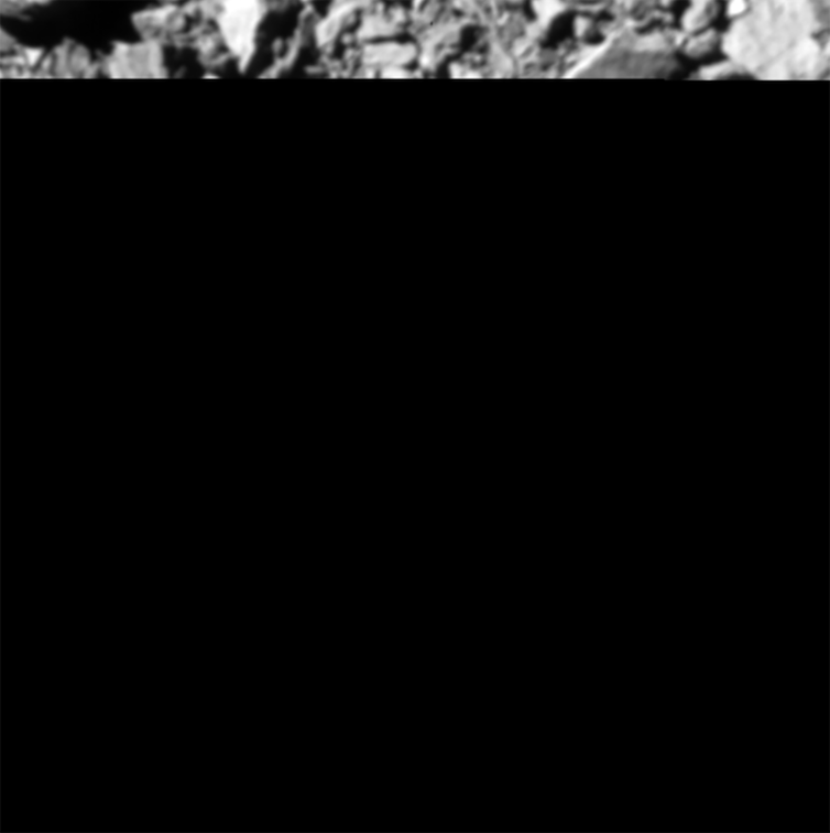 A slice of a photo of a gray, rocky surface with the rest of image black.