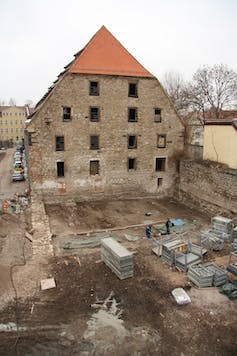four story medieval building with excavated dirt in foreground
