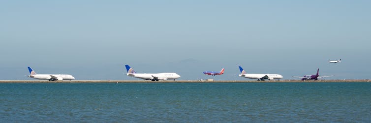 A number of planes line up for takeoff on a runway.