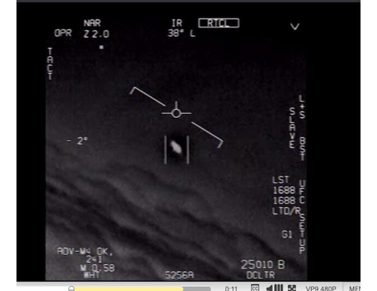 A screenshot from a Navy video taken by a pilot showing a white, mysterious craft in the sky.