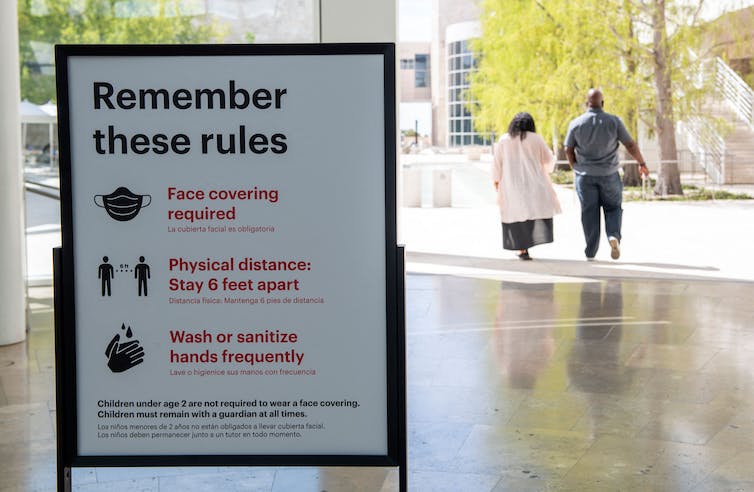 A sign telling people to wear masks, stay 6 feet apart and wash hands.