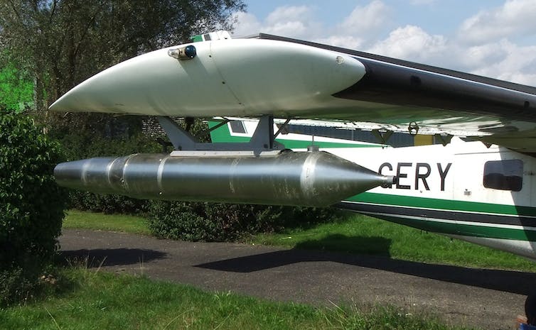 A plane wing with a cylindrical device attached.