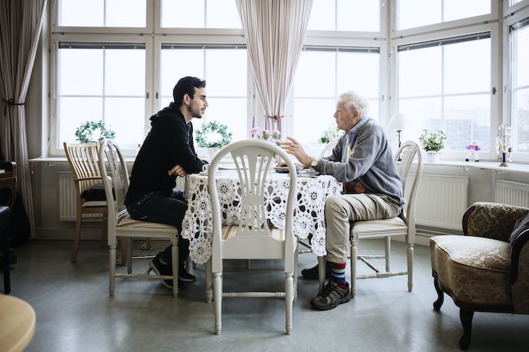 younger and older man in discussion across dining table