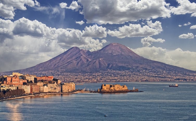 A photograph of the city of Naples, Italy, with Mount Vesuvius in the background.