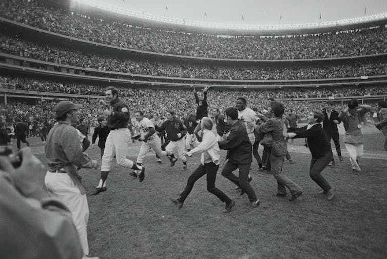 Fans race around a baseball field.