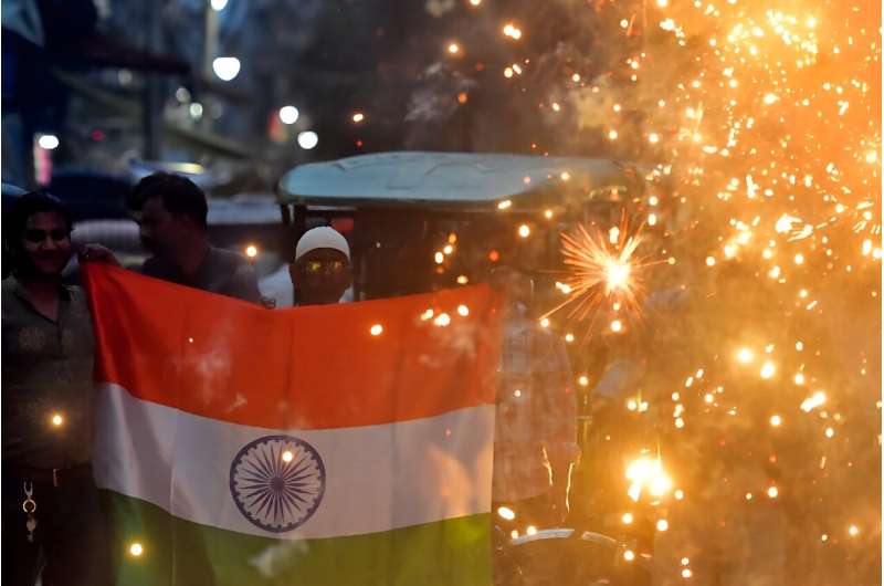 A man holds India's national flag amid firecrackers in Prayagraj to celebrate the successful lunar landing of Chandrayaan-3 spac