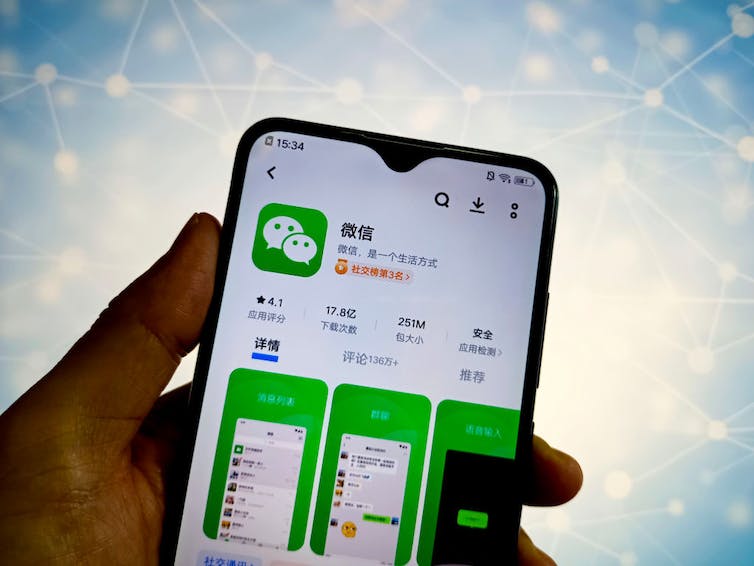 A hand holding a phone displaying an app store page for WeChat
