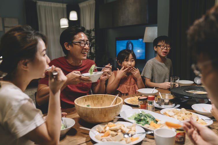 Family smiling and eating together around a dinner table