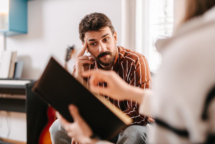 man with hand to his head looking glum