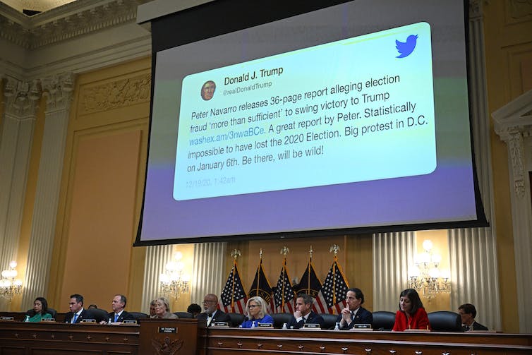 A projection of text on a large screen above a row of seated people