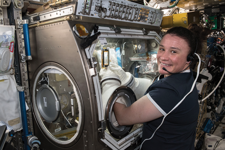 A woman smiles while working on an experiment aboard the International Space Station.