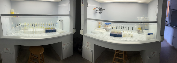 Two fume hoods with vials of sample under them.