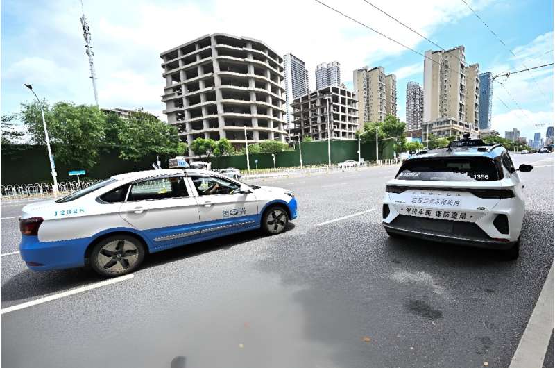 A regular taxi overtakes a driverless one in Wuhan, home to one of the world's largest robotaxi networks