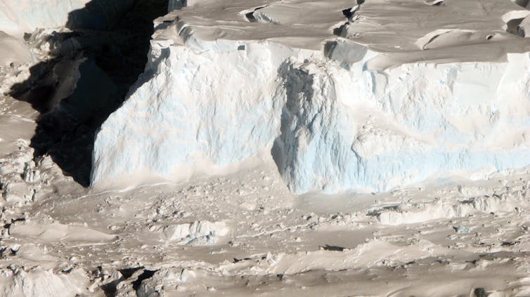 An aerial photo of the tall front of Thwaites' ice shelf, where icebergs calve off into the ocean.