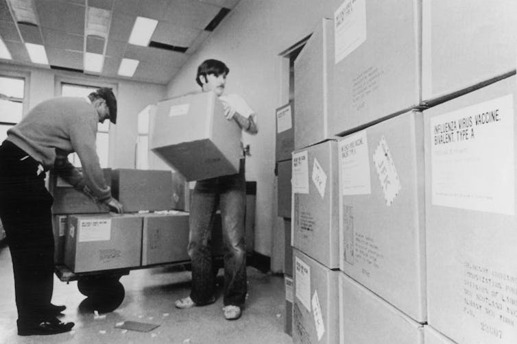 piles of cardboard boxes and two men lifting them