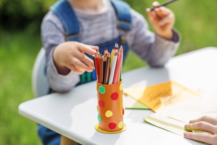 Child considering a container of colored pencils