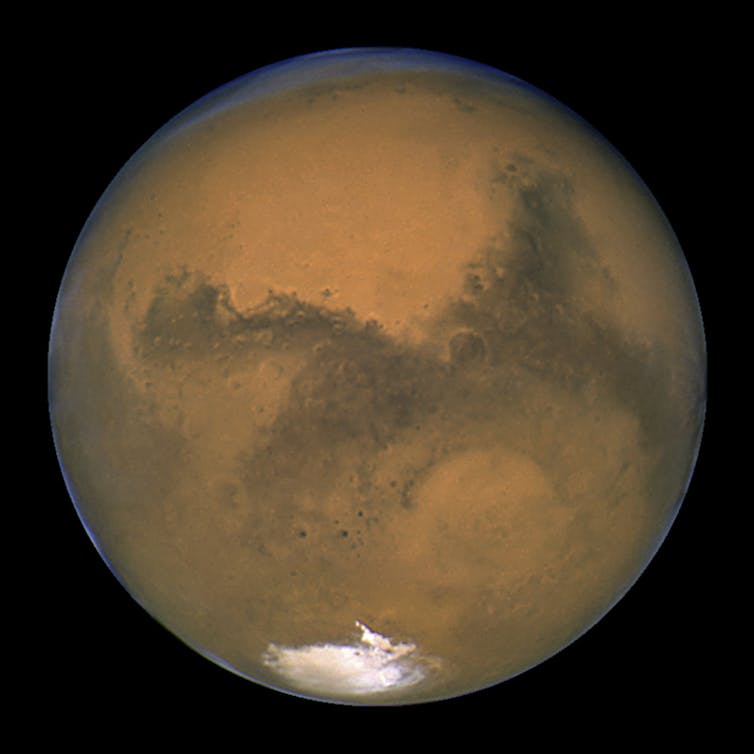 Mars, a dusty reddish planet, floating in space.