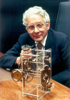 Derek de Solla Price wearing glasses and sitting in a chair with a metal device.