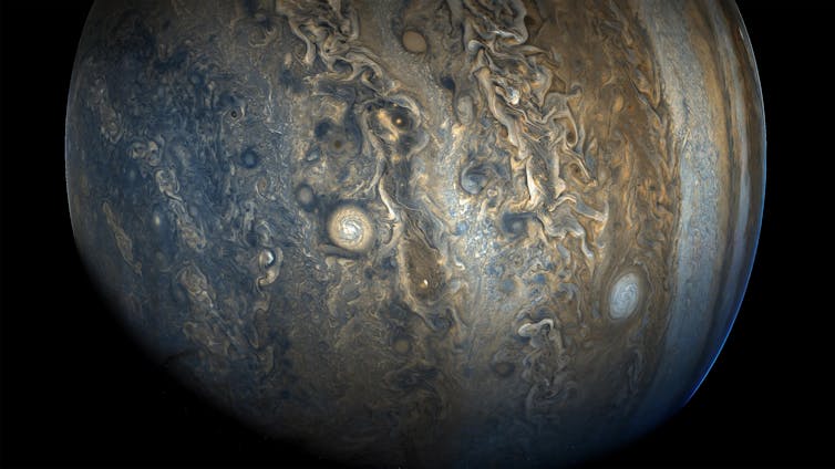 A photograph of the planet Jupiter swathed in blue, brown and gold bands.