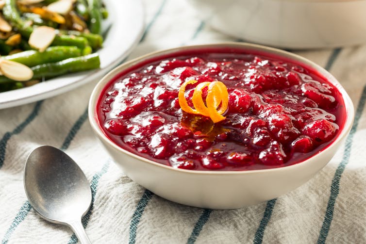 A bowl of cranberries with the zest of an orange on top.