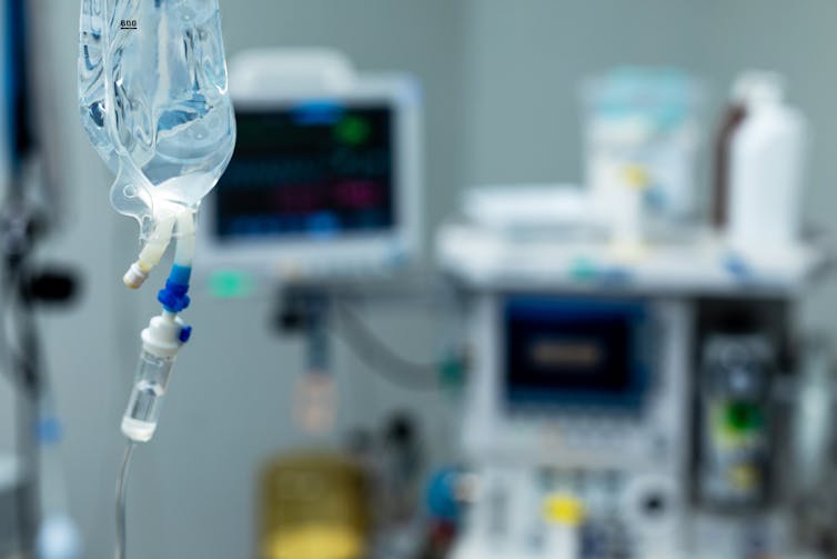 Close-up of IV bag with other medical equipment in the background out of focus