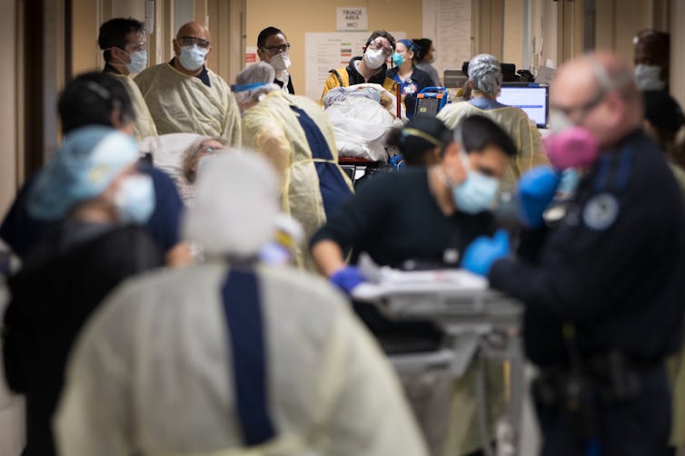 lots of people wearing PPE in a hospital hallway