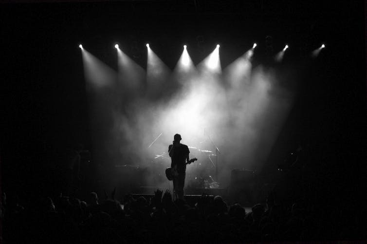 Silhouette of a band's lead singe under the spotlights on a stage