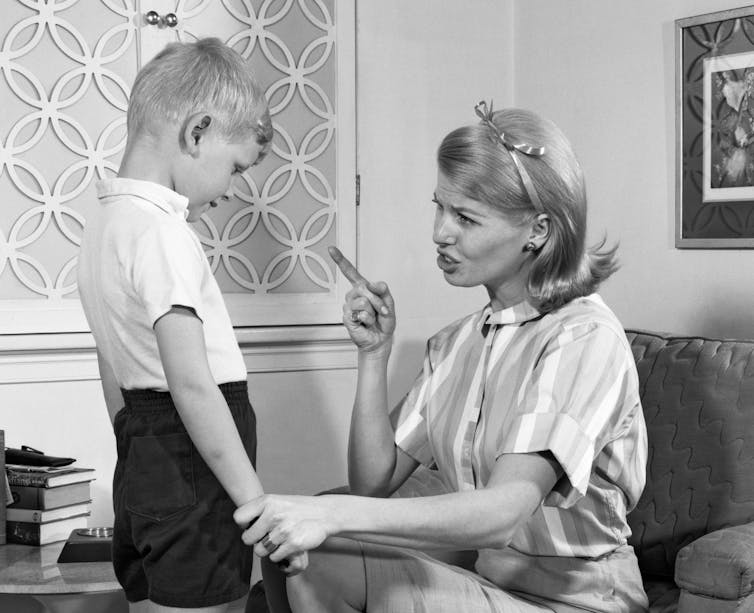 Black and white image of a mom disciplining son.