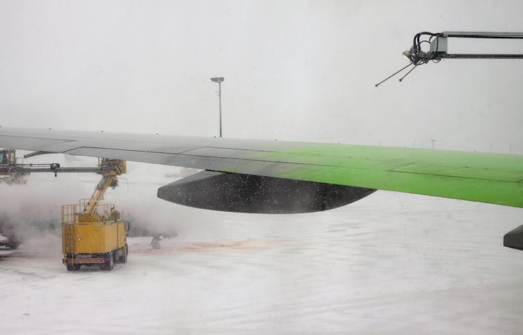 a plane wing is sprayed with green liquid.