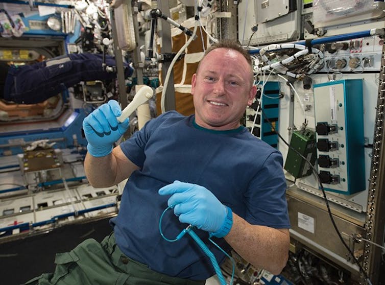An astronaut holding a wrench poses for the camera.