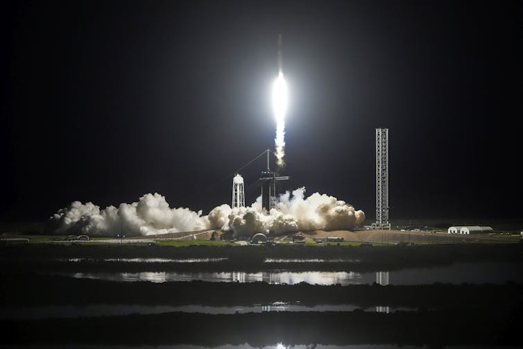 A rocket launching into a dark sky, leaving behind a cloud of smoke.
