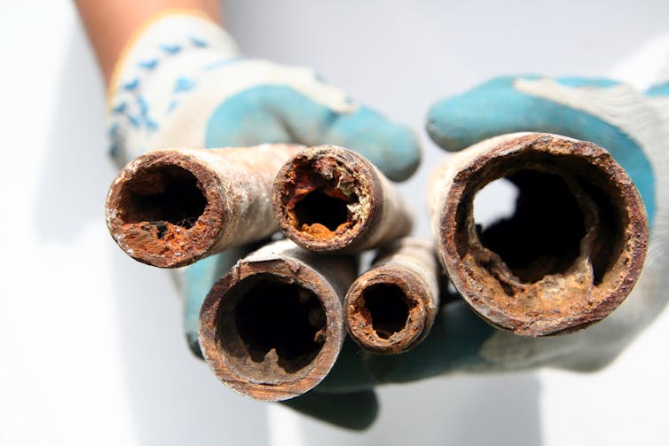 Five old pipes held together, showing their corroded and clogged insides