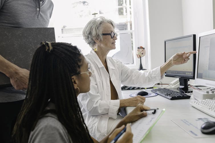 Two women, one older and one younger, sitting in front of a computer screen.