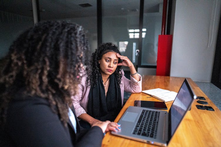 worried woman seated with another looking at a laptop