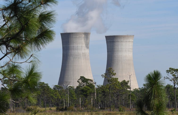 Large concrete towers emit vapor into the atmosphere.