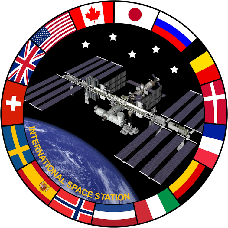 An emblem featuring a photo of the ISS with a ring around it featuring countries' flags.