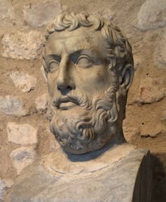 A stone bust of a man with curly hair and a beard.