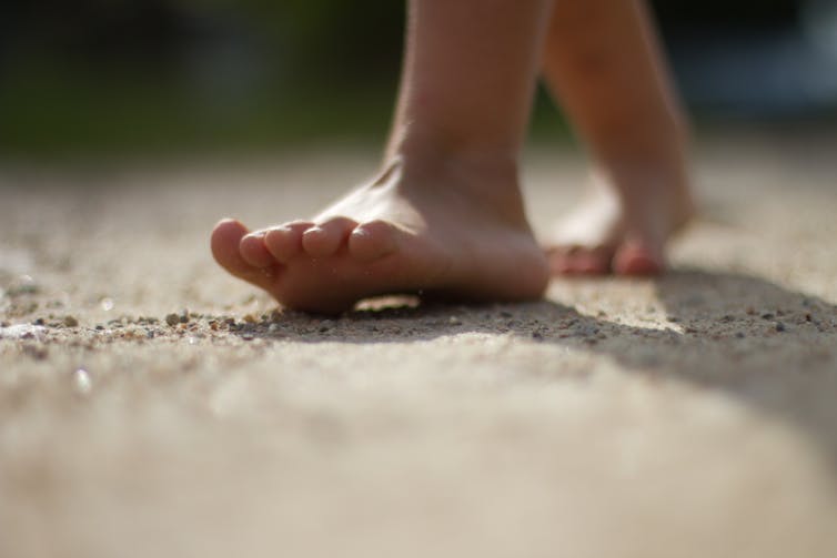 bare feet walking across sandy surface toward camera