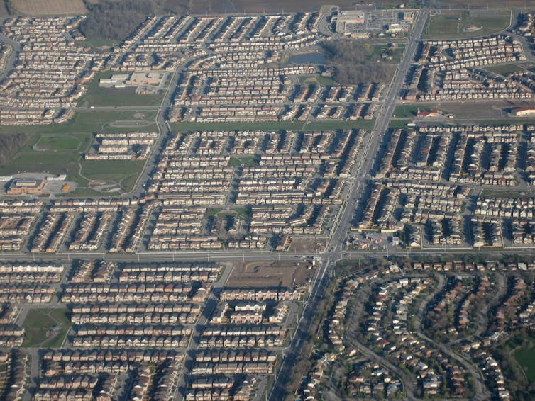 An overhead shot of a neighborhood made up of neat lines of houses and roads.